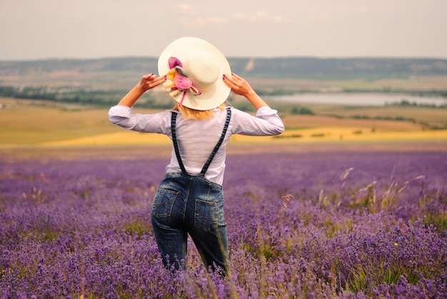 Jovem de macacão jeans e vestido branco em um campo de lavanda