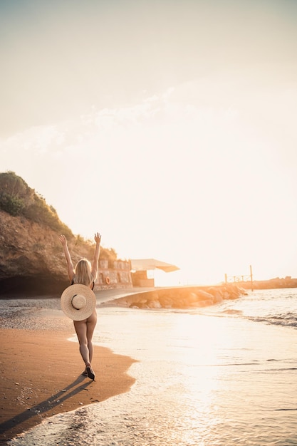 Jovem de maiô com uma bela figura à beira-mar ao pôr do sol foco seletivo