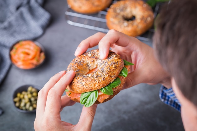 Jovem de mãos dadas e pronto para comer bagels com salmão defumado