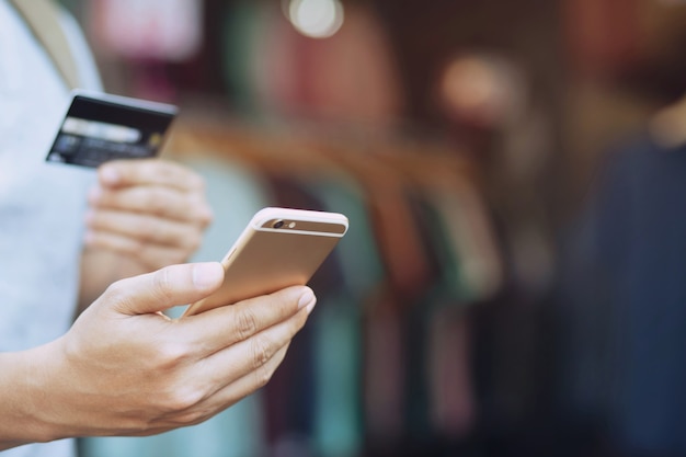 Foto jovem de óculos, compras online com cartão de crédito, usando o telefone inteligente em casa.