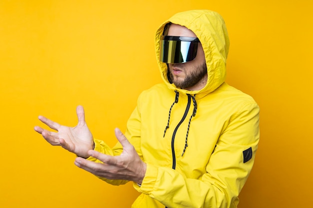 Jovem de óculos cyberpunk clicando em uma tela invisível em um fundo amarelo