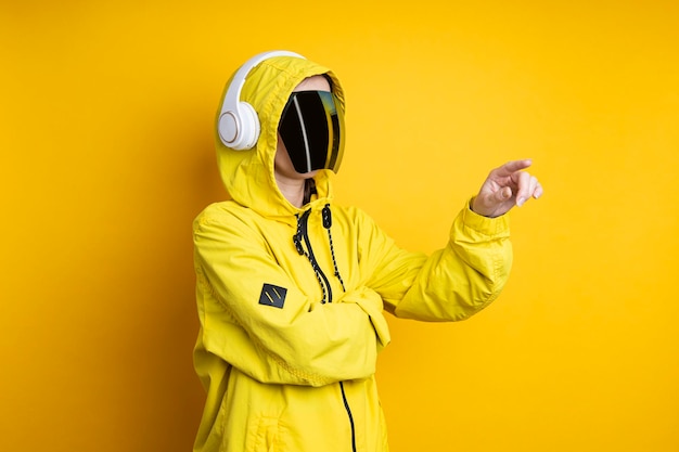 Jovem de óculos cyberpunk com fones de ouvido clica em uma tela virtual em um fundo amarelo