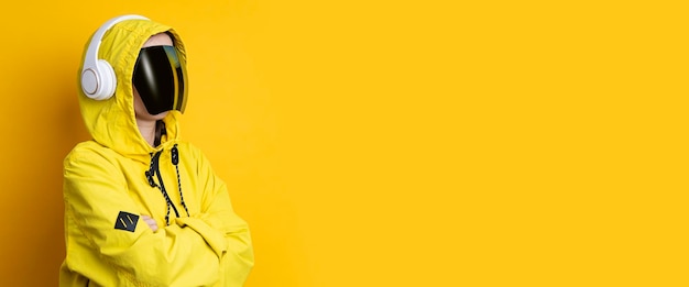 Jovem de óculos cyberpunk com fones de ouvido em uma jaqueta amarela em um fundo amarelo Banner