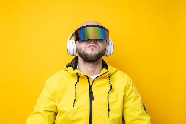 Jovem de óculos cyberpunk em uma jaqueta amarela com fones de ouvido em um fundo amarelo