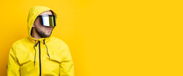 Jovem de óculos cyberpunk em uma jaqueta amarela olhando para longe em um fundo amarelo Banner