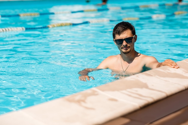 Jovem de óculos de sol na piscina