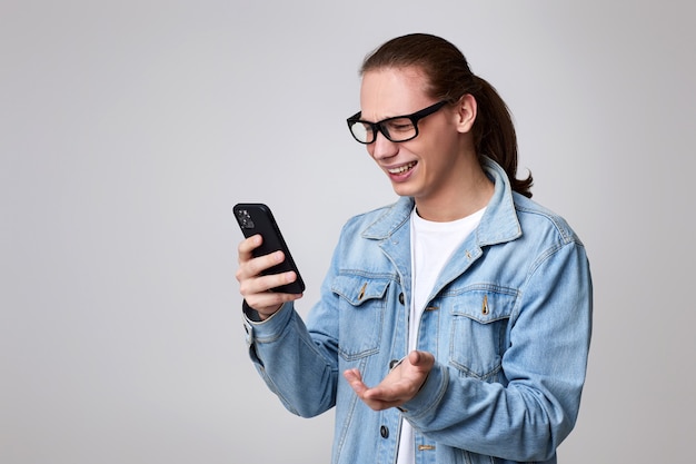 Jovem de óculos e jaqueta jeans usando smartphone