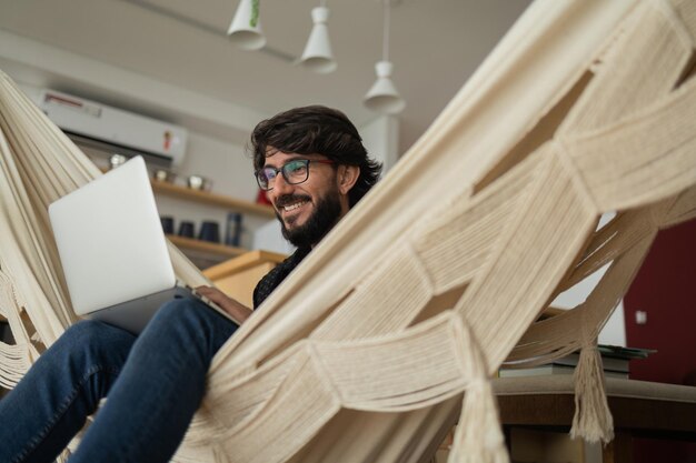 Foto jovem de óculos pretos trabalhando com laptop em um caderno branco para trabalhar em escritório em casa