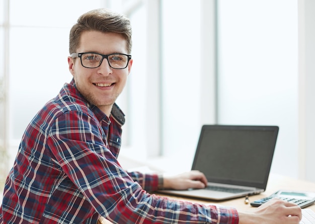 Jovem de óculos trabalhando em seu notebook tirando o negócio do caminho