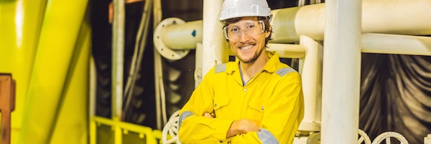 Jovem de óculos uniforme de trabalho amarelo e capacete na plataforma industrial de óleo ambiental ou