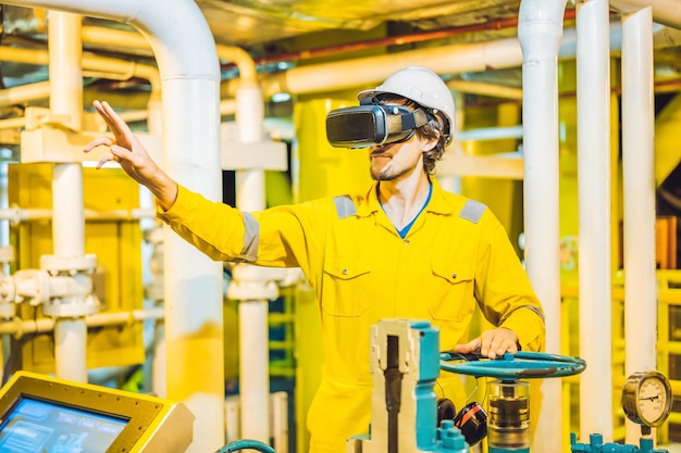 Jovem de óculos uniforme de trabalho amarelo e capacete usa óculos de realidade virtual em indústria