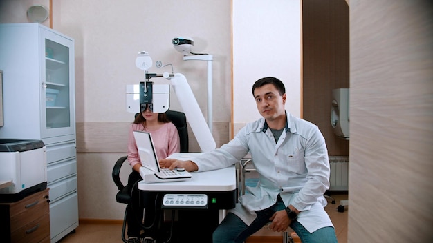 Jovem de oftalmologia verificando sua acuidade visual com um equipamento optometrista um médico sentado perto