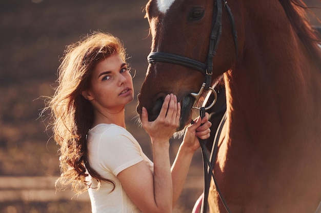 Jovem de pé com seu cavalo no campo de agricultura em dia ensolarado