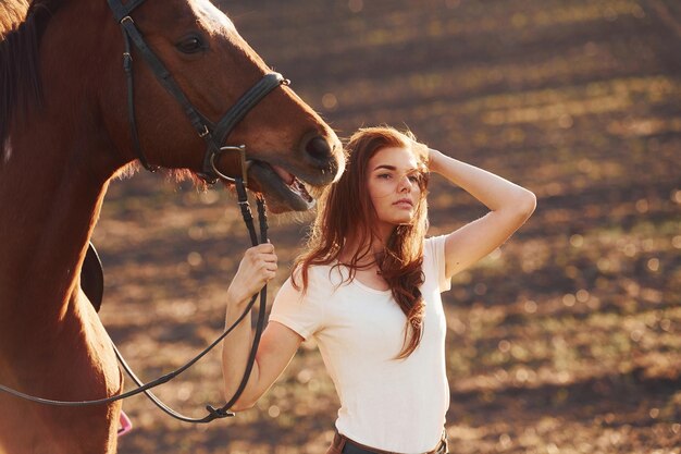 Jovem de pé com seu cavalo no campo de agricultura em dia ensolarado