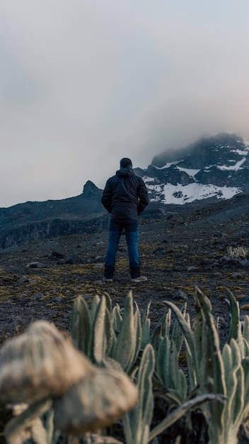 Jovem de pé em cima de pedra e desfrutando de incrível montanha vulcânica