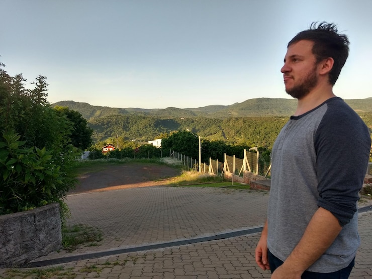 Foto jovem de pé junto a uma árvore contra o céu