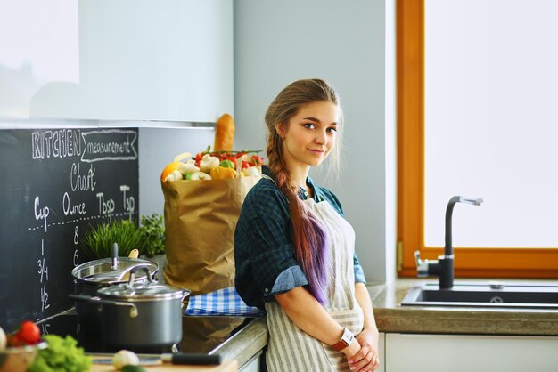 Jovem de pé junto ao fogão na cozinha