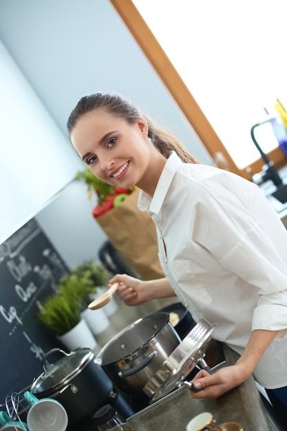 Jovem de pé junto ao fogão na cozinha