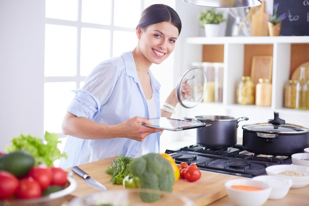 Jovem de pé junto ao fogão na cozinha