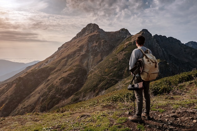 Jovem de pé no topo de montanhas do penhasco