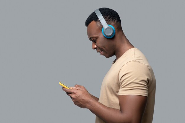 Jovem de pele escura usando fones de ouvido ouvindo música