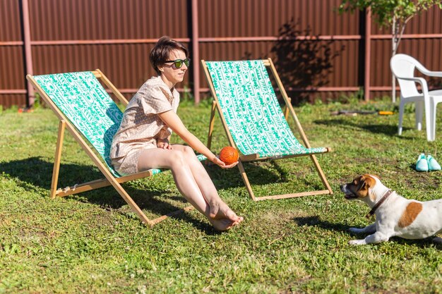 Jovem de pijama está descansando na cadeira em um gramado verde na vila ensolarada do dia de verão e na vida no campo