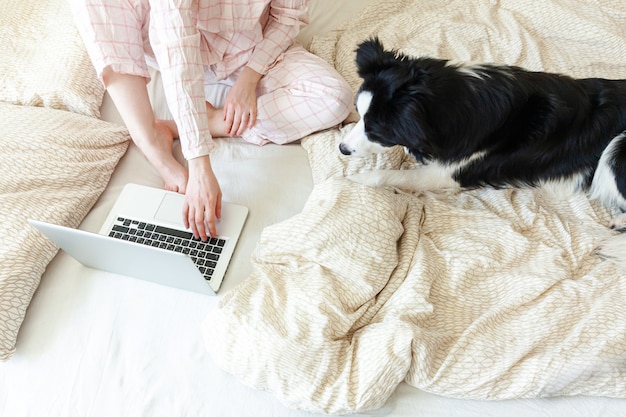 Jovem de pijama, sentada na cama com cachorro