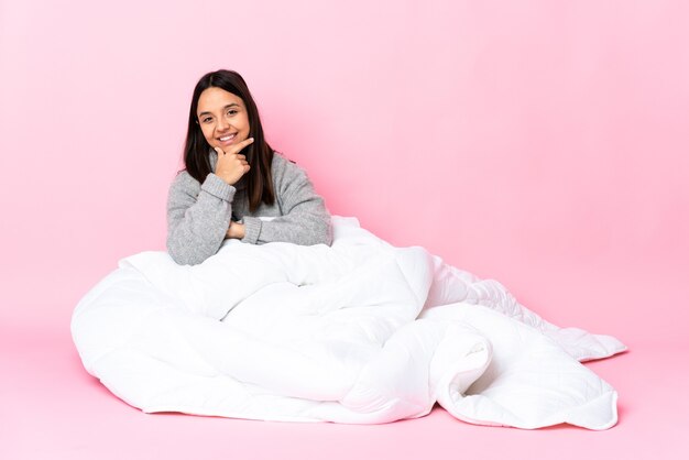 Jovem de pijama sentada no chão feliz e sorridente