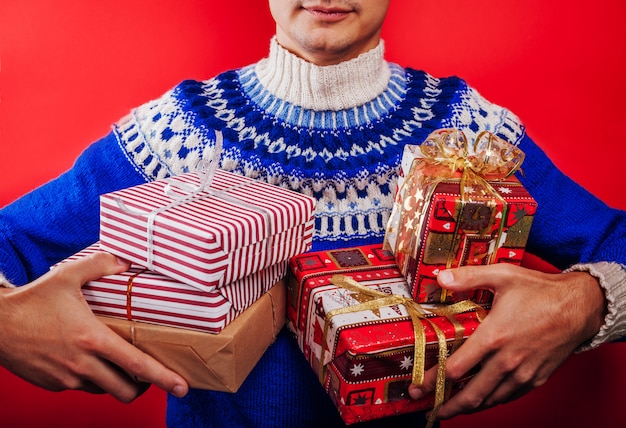 Jovem de suéter islandês segurando uma pilha de caixas de presente. conceito de celebração de natal.