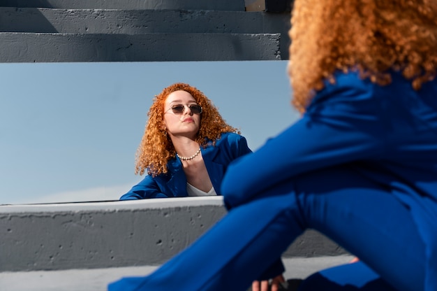 Foto jovem de terno azul posando com espelho ao ar livre