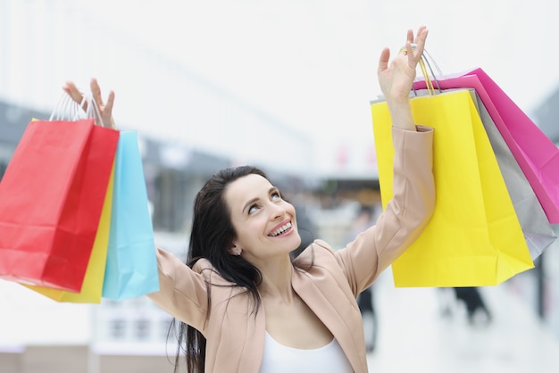 Jovem de terno pegando muitos sacos de papel coloridos com as compras