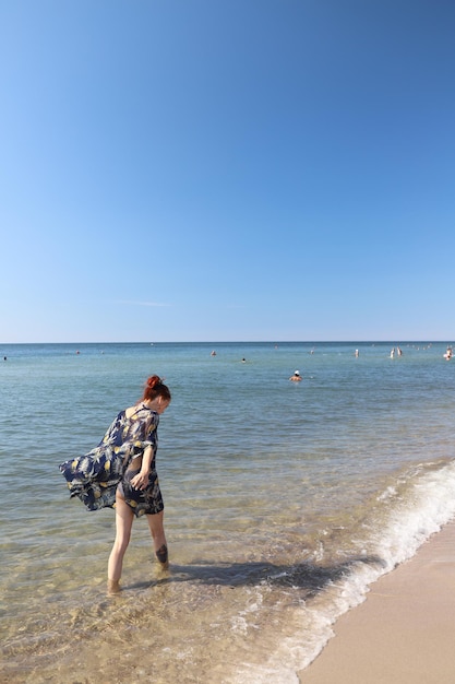 Jovem de vestido andando na praia