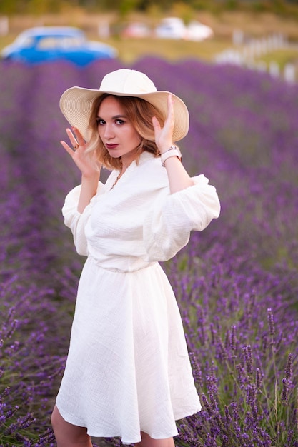 Jovem de vestido branco e chapéu de palha correndo em um campo de lavanda