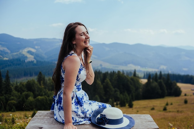 Jovem de vestido elegante descansando no banco nas montanhas