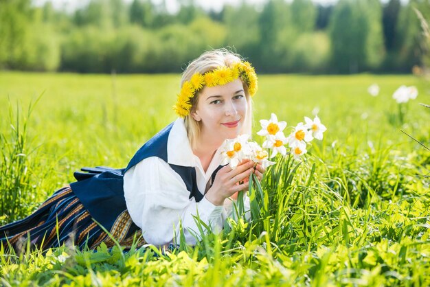 Jovem de vestido nacional em um campo com flores de narcisos