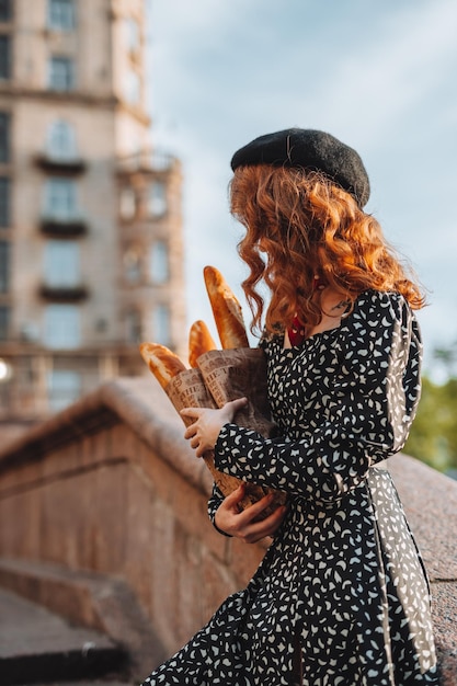 Jovem de vestido preto segurando um pacote de papel de baguetes francesas foto de comida de padaria de pão