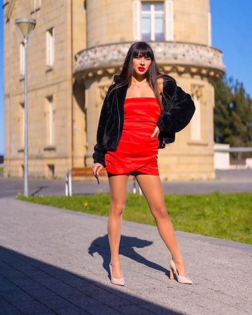 Jovem de vestido vermelho no belo castelo andando em pose de moda