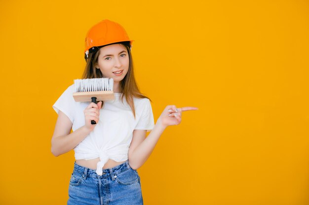 Jovem decorador feminino com rolo de pintura em fundo amarelo