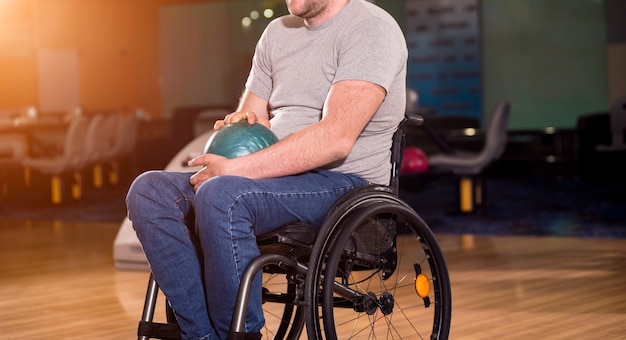 Jovem deficiente em cadeira de rodas jogando boliche no clube