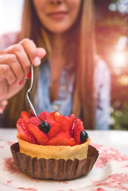 Foto jovem degustando bolo com frutas vermelhas foco seletivo