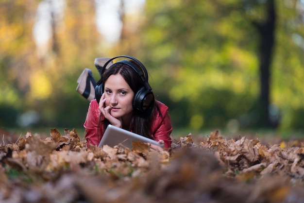 Jovem deitada do lado de fora e ouvindo fones de ouvido