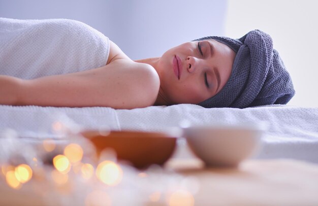 Jovem deitada em uma mesa de massagem relaxando com os olhos fechados salão de spa mulher