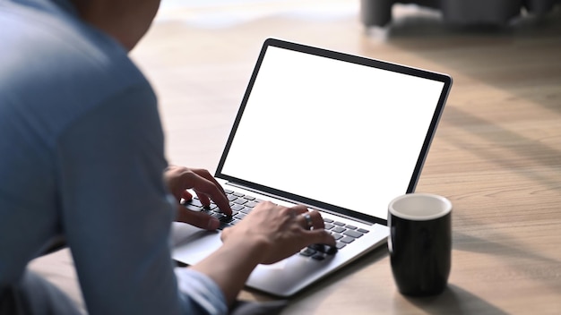 Jovem deitado no chão de madeira e usando o laptop do computador.