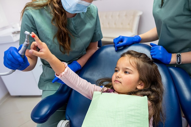 Jovem dentista especialista qualificada escovando os dentes de uma criança pequena que foi trazida para a recepção O conceito de escovar os dentes do bebê