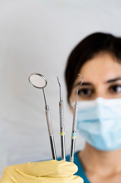 Jovem dentista feminina segurando instrumentos dentários na mão