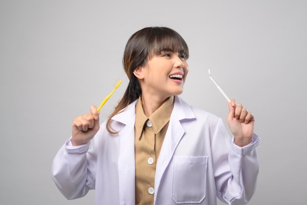Jovem dentista feminina sorrindo sobre estúdio de fundo branco