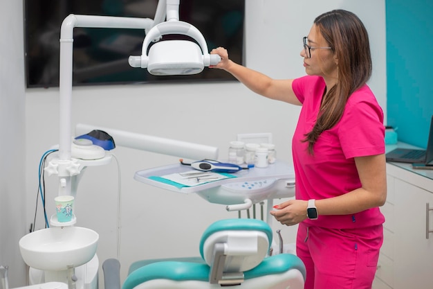 Jovem dentista preparando seu equipamento no consultório dentário