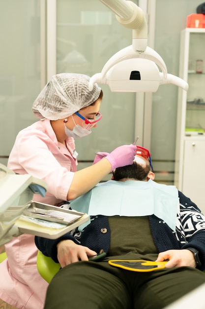 Jovem dentista trata paciente um homem.