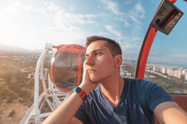 Jovem deprimido e triste tirando selfie enquanto andava na roda gigante no parque de diversões luna Solidão e conceito de depressão