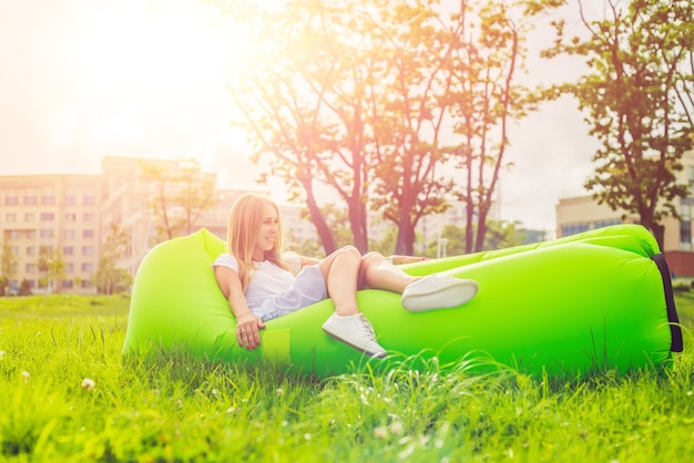 Jovem descansando em um sofá de ar no parque.